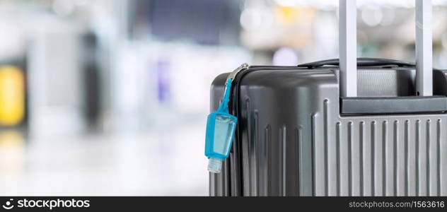 Luggage bag with alcohol gel hand sanitizer in international airport terminal, protection Coronavirus disease (Covid-19) infection. New Normal and travel bubble concepts