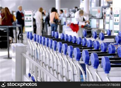Luggage carts at modern international airport passengers at check-in counter in the background