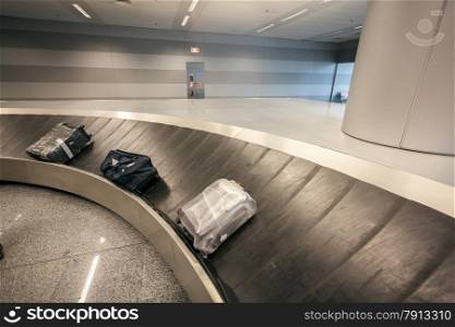 Luggage claim carousel with three bags at airport terminal