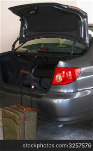 Luggage sitting outside car with open trunk