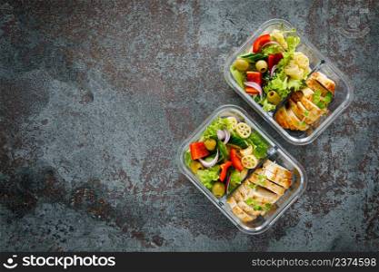 Lunch boxes with grilled chicken breast and pasta salad with fresh vegetables. Top view