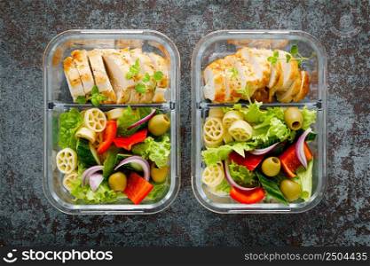 Lunch boxes with grilled chicken breast and pasta salad with fresh vegetables, top view