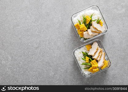 Lunch boxes with grilled chicken breast, rice, corn and green beans. Top view, flat lay