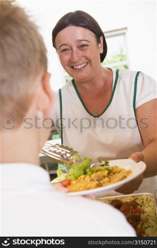Lunch lady serving salad to student