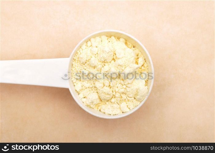 Lupin flour in measuring spoon on brown background