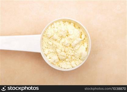 Lupin flour in measuring spoon on brown background