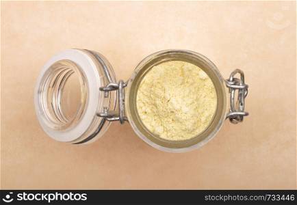 Lupin flour in open jar on brown background