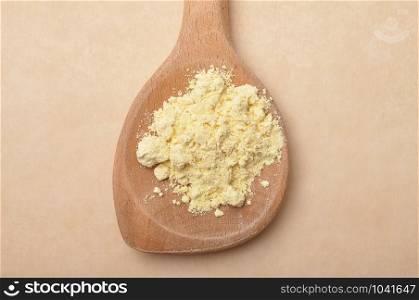 Lupin flour on wooden spoon on brown background