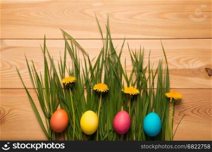 lush grass and dandelions in the composition with Easter eggs on a wooden table