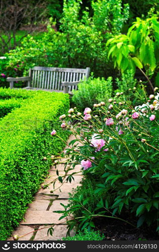 Lush green garden with stone landscaping, flowers, hedge and bench