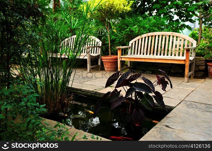 Lush green garden with stone landscaping, koi pond and benches