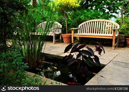 Lush green garden with stone landscaping, koi pond and benches