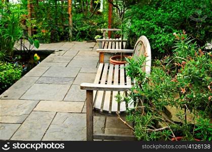 Lush green garden with stone landscaping, pond and benches