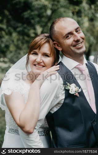 Lutsk, Volyn / Ukraine - : Bride looking out from behind the groom?s shoulder in park