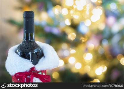 Luxurious holiday composition, a bottle wine with a Christmas tree and bokeh lights on the background with copy space, Holiday concept space for text. Luxurious holiday composition, a bottle wine with a Christmas tree and bokeh lights on the background with copy space, Holiday concept