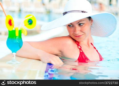 Luxurious woman in a hat and cocktail