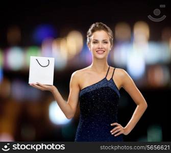 luxury, advertisement, holidays and sale concept - smiling woman with white blank shopping bag over night lights background