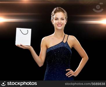 luxury, advertisement, holidays and sale concept - smiling woman with white blank shopping bag over night lights background