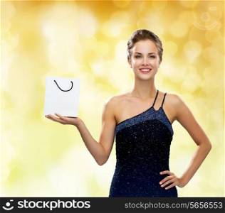 luxury, advertisement, holydays and sale concept - smiling woman with white blank shopping bag over yellow lights background