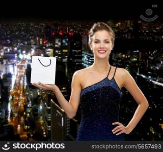 luxury, advertisement, holydays and sale concept - smiling woman with white blank shopping bag over night city background