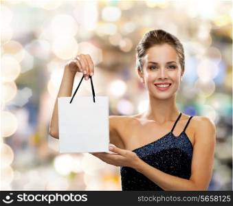 luxury, advertisement, holydays and sale concept - smiling woman with white blank shopping bag over lights background