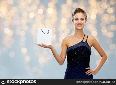 luxury, advertisement, holydays, people and sale concept - smiling woman with white blank shopping bag over lights background