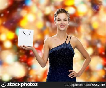 luxury, advertisement, winter holidays, christmas and sale concept - smiling woman with white blank shopping bag over red lights background
