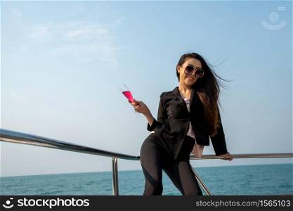 Luxury asian woman in black suit drinking champagne on the yacht.