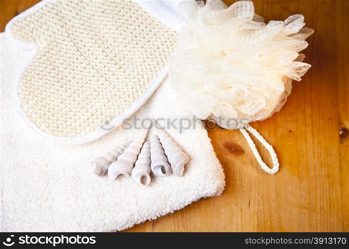 Luxury bath or shower set with towel, glove, sponge and shells on wooden background