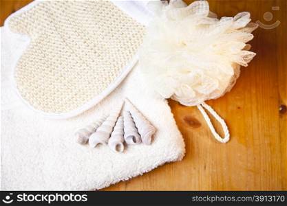 Luxury bath or shower set with towel, glove, sponge and shells on wooden background
