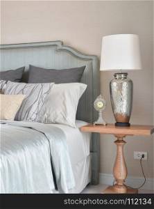 luxury bedroom interior with decorative table lamp and alarm clock on bedside table