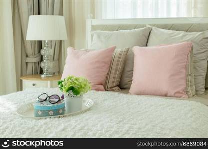 luxury bedroom interior with pink pillows and white tray of flower on bed