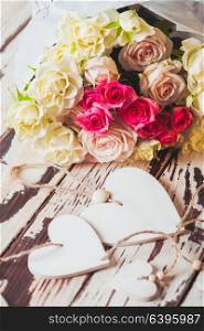 Luxury bouquet of roses lying on a wooden board and wooden hearts. Bouquet of roses