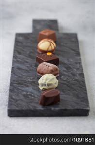 Luxury Chocolate candies selection on black marbel board. White, dark and milk chocolate assortment. Top view
