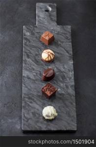Luxury Chocolate candies selection on black marbel board. White, dark and milk chocolate assortment. Top view