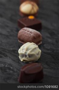 Luxury Chocolate candies selection on black marbel board. White, dark and milk chocolate assortment. Macro