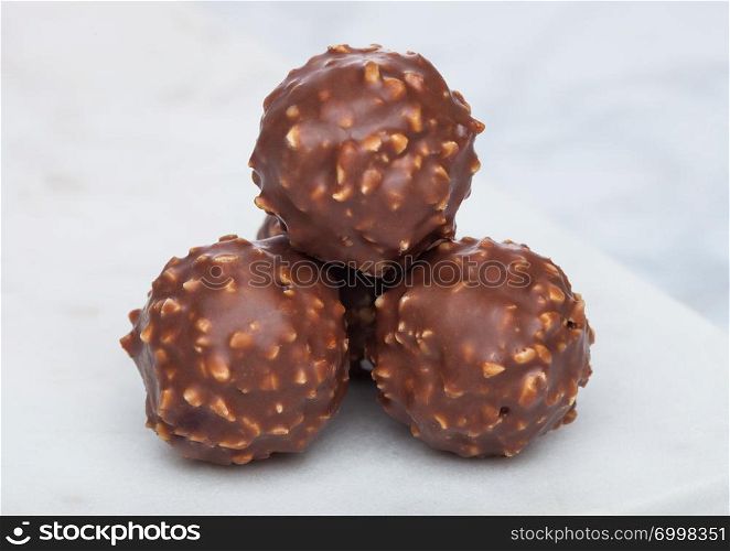 Luxury chocolate candies with hazelnuts on marble board and white.