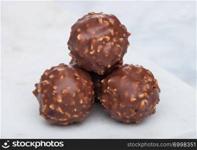 Luxury chocolate candies with hazelnuts on marble board and white.