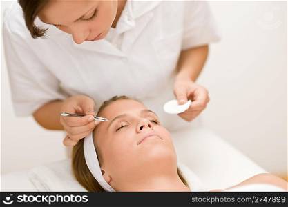 Luxury cosmetics - woman having facial, beautician using tweezers