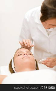 Luxury cosmetics - woman having facial, beautician using tweezers