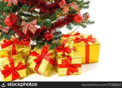 Luxury golden colored gifts with red ribbon under a beautiful christmas tree with red balls, bows and lights isolated on white background in close-up
