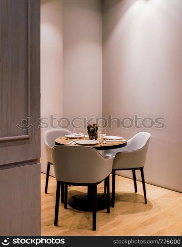 luxury interior modern dinner chairs and table with setting, small cactus pot and wine glass under warm light