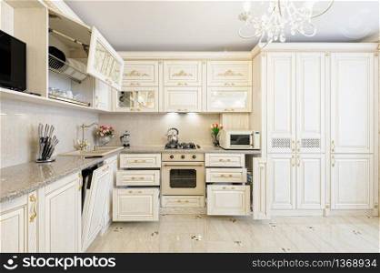 Luxury modern beige and cream colored kitchen in modern classic style. Some drawers are open. Luxury modern beige and cream colored kitchen interior