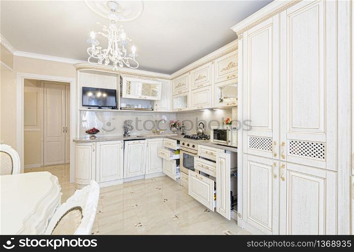 Luxury modern beige and cream colored kitchen in modern classic style. Some drawers are open. Luxury modern beige and cream colored kitchen interior