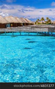 Luxury resort in Maldives, little wooden bungalows over blue transparent water, spending summer vacation on Indian ocean