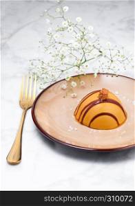 Luxury restaurant caramel dessert on plate with golden fork and flowers