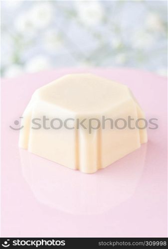 Luxury square white chocolate candy on pink plate on flowers background