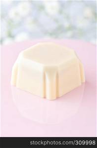 Luxury square white chocolate candy on pink plate on flowers background