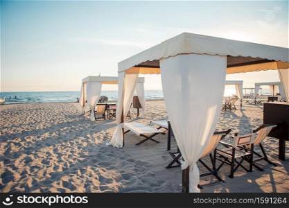 Luxury sun beds on the beach. Beach loungers in famous italian seashore. Luxury sun beds in the evening lights