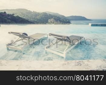 Luxury swimming pool and blue water at the resort with beautiful sea view (Vintage filter effect used)